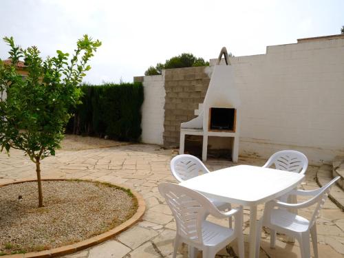 Villa Villa Palma by Interhome في Les tres Cales: طاولة بيضاء وكراسي في فناء مع شواية