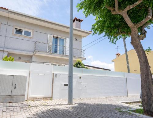 a house with a white fence and a tree at Villa Amor Perfeito in Vila do Conde