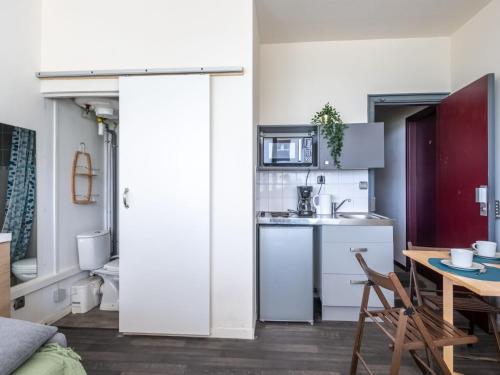 - une cuisine avec des placards blancs, une table, une table et des chaises dans l'établissement Studio Chéops-2 by Interhome, à La Grande Motte