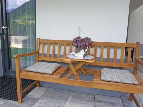 a wooden bench sitting on a porch with a vase of flowers at Apartment Jonas by Interhome in See