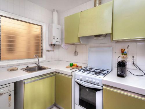 cocina con armarios verdes y fogones horno superior en Apartment Can Panxo by Interhome, en L'Escala