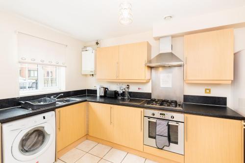 a kitchen with wooden cabinets and a washer and dryer at Great 4 bed house in Black Country in Tipton
