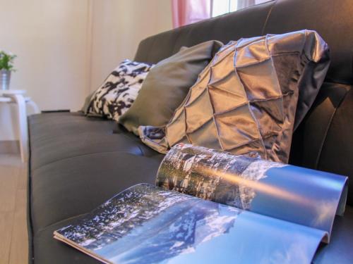 a black couch with pillows and a book on it at Apartment Grenat 8 by Interhome in Villars-sur-Ollon