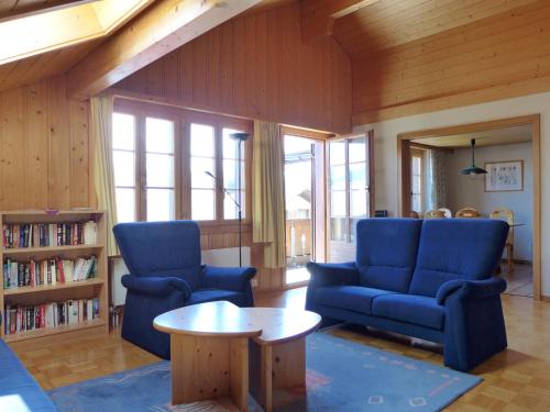 - un salon avec des chaises bleues et une table dans l'établissement Apartment Chalet Burgfeld by Interhome, à Beatenberg