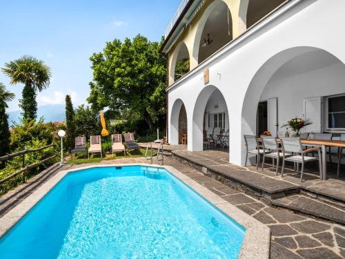 una piscina nel cortile di una casa con tavolo e sedie di Holiday Home Vernice Gialla-1 by Interhome a Minusio