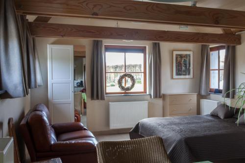 a bedroom with a bed and a chair and a window at Cleensyde in Horebeke