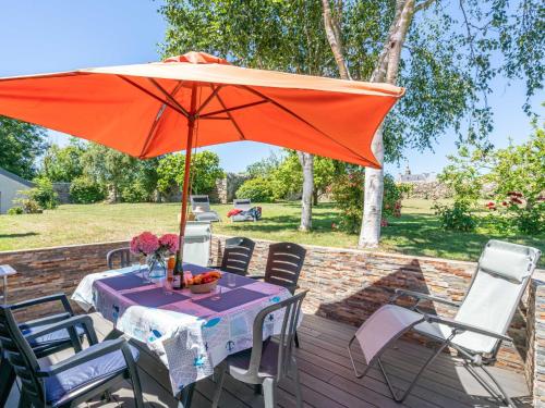 a table with an orange umbrella on a deck at Holiday Home Ty ar Bilie by Interhome in Primelin
