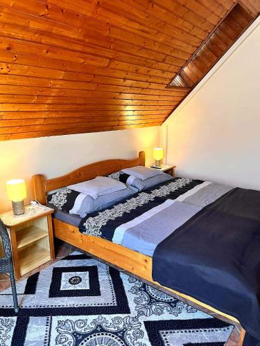 a bedroom with a large bed and a wooden ceiling at Dóra Stúdió Apartmanok in Zalakaros