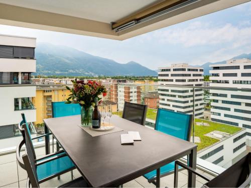 een eetkamer met een tafel en stoelen en een balkon bij Apartment LocTowers A4-8-2 by Interhome in Locarno