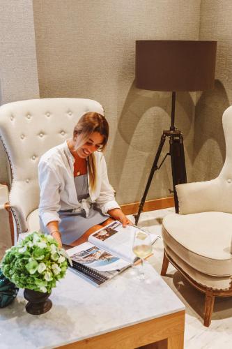 a woman sitting at a table looking at a magazine at Boutique Hotel Casa del Mare - Vizura in Kotor
