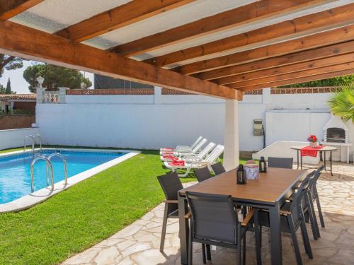 een terras met een tafel en stoelen en een zwembad bij Villa Neus by Interhome in Lloret de Mar
