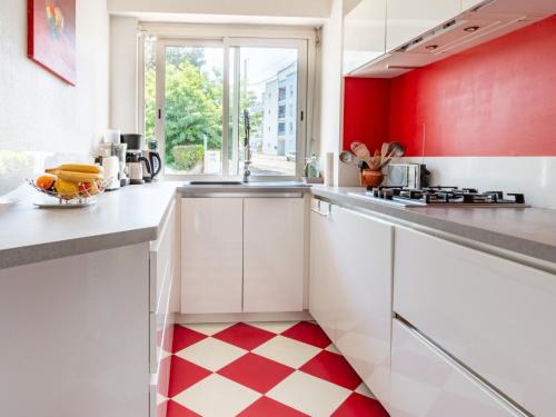 une cuisine avec des armoires blanches et des murs rouges et un sol à carreaux dans l'établissement Apartment Les Pêcheries by Interhome, à Saint-Nazaire