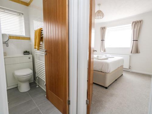 a bathroom with a toilet and a bed in a room at Sandpiper in Weymouth