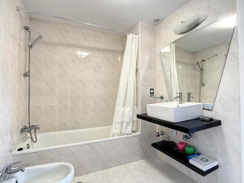 een badkamer met een wastafel, een bad en een spiegel bij Vista Mar by Atlantic Holiday in Caniço