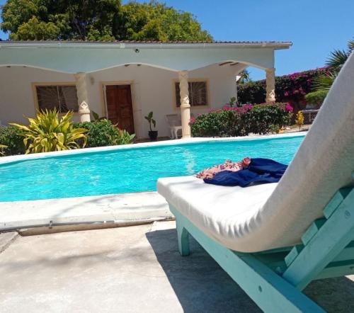 uma cadeira ao lado de uma piscina em 2 Bedroom Mangrove Cottage with Private Pool em Watamu