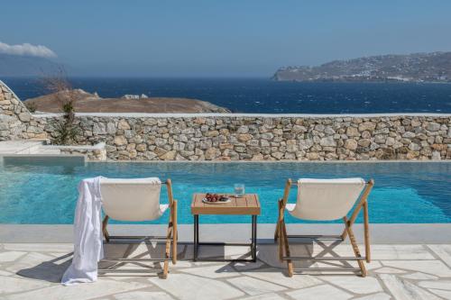 two chairs and a table next to a pool at Mykonos Esti Luxury Villas in Agios Ioannis Mykonos