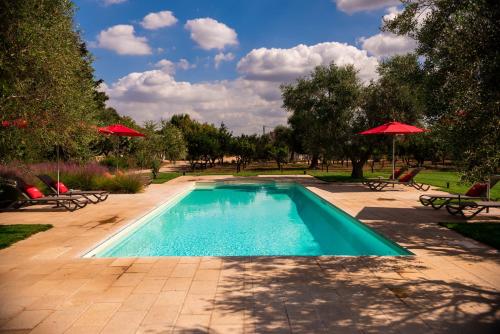 a swimming pool with chairs and umbrellas in a park at Masseria Li Reni in Manduria
