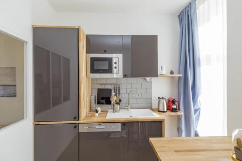 une petite cuisine avec un réfrigérateur et un évier dans l'établissement JOLI 23 m Lumineux et Rénové PROCHE Sacré-Cœur, à Paris