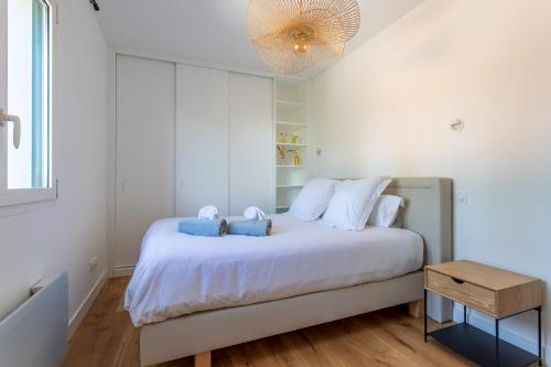 - une chambre avec un grand lit blanc et des oreillers bleus dans l'établissement Pyla Plage - appartement vue mer - Perle(o), à La Teste-de-Buch