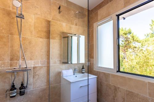 La salle de bains est pourvue d'un lavabo, d'une douche et d'une fenêtre. dans l'établissement Pyla Plage - appartement vue mer - Perle(o), à La Teste-de-Buch