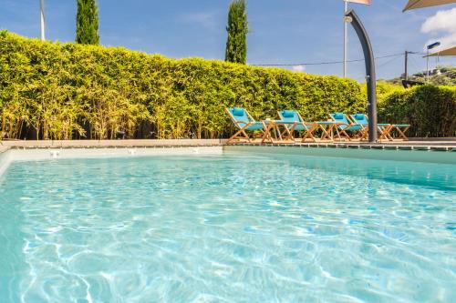a swimming pool with blue chairs and trees at Rossi Hôtel in Sartène