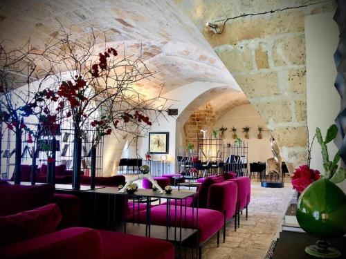 a room with purple chairs and tables and a stone wall at Masseria Li Reni in Manduria