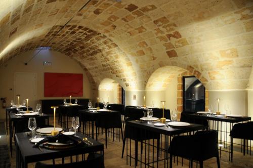 a dining room with tables and chairs and a brick wall at Masseria Li Reni in Manduria