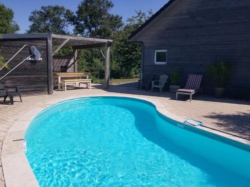 a swimming pool in a yard next to a house at Gîte de la Tuillère, maison contemporaine en bois avec vue et piscine in Saint-Aulaire