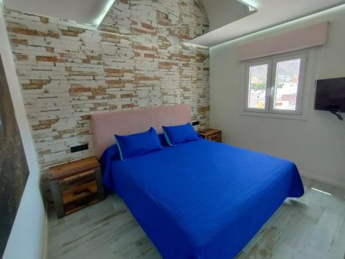 um quarto com uma cama azul e uma parede de tijolos em Apartamento en primera línea de mar, las Teresitas, Santa Cruz de Tenerife em San Andrés