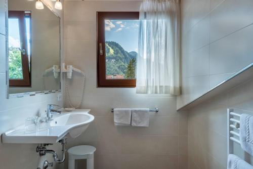 a white bathroom with a sink and a window at Hotel Residence Gardena Saslong in Santa Cristina in Val Gardena