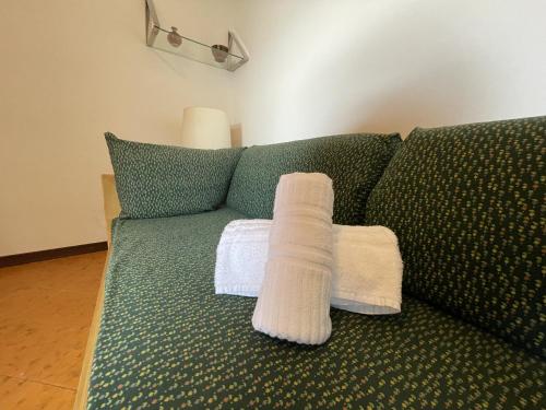 eine grüne Couch mit zwei weißen Handtüchern drauf in der Unterkunft Suite Semeria 130 - Relax, Mare, Parking in Sanremo