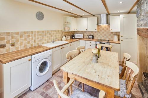 a kitchen with a table and a washing machine at Host & Stay - Eden Cottage in Holy Island
