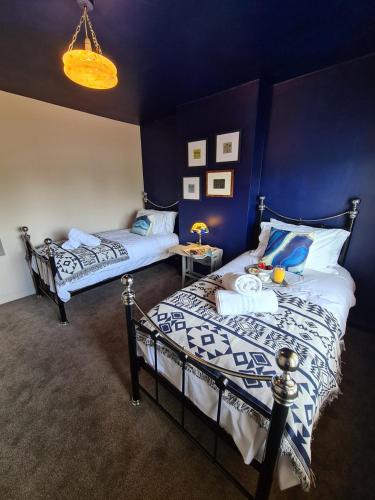 two beds in a room with blue walls at Rumer Hill House a unique boutique styled place to stay in Cannock close to A5 the McArthur Glen outlet in Great Wyrley