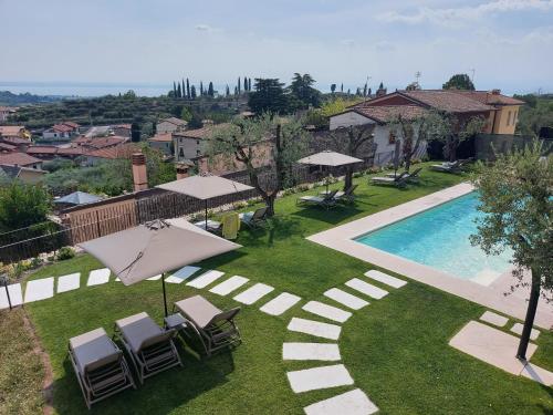 uma piscina com cadeiras e guarda-sóis ao lado de uma casa em Il cantuccio sul Garda - Relais di charme em Cavaion Veronese