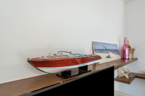 - un bateau en bois sur une étagère à côté d'une télévision dans l'établissement Alle Rive apartment, à Salò