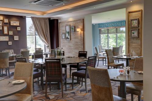 a dining room with tables and chairs and windows at Castle Green Hotel In Kendal, BW Premier Collection in Kendal