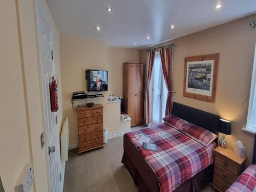 a bedroom with a bed and a dresser and a television at Town House B & B in Skipton