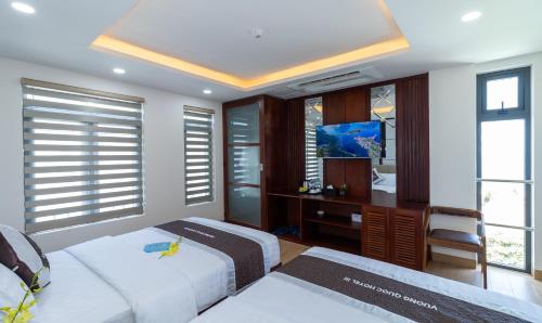 a bedroom with two beds and a desk and windows at Vương Quốc 3 Hotel in Quy Nhon