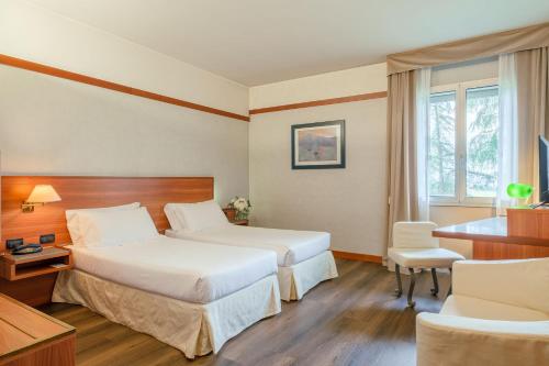 ゾーラ・プレドーザにあるSHG Hotel Bolognaのベッド2台とデスクが備わるホテルルームです。