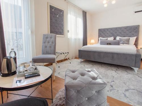 a bedroom with a bed and a table and a chair at Villa Malkoc - Luxury rooms & apartments in Mostar