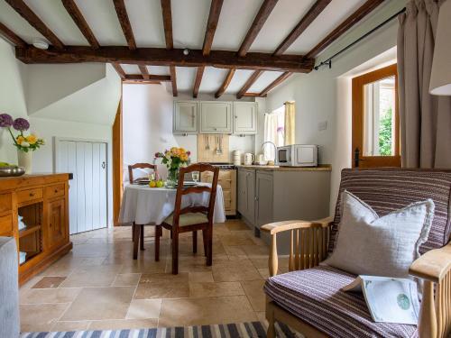 a living room with a table and a kitchen at Climbing Rose Cottage - Dog Friendly - Peaceful Cotswold Cottage in Adlestrop
