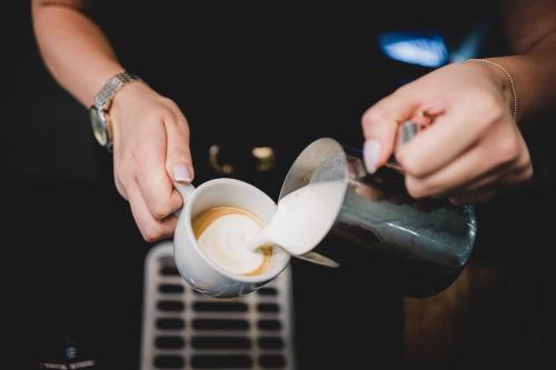 a person is pouring coffee into a cup at Hotel Filmar in Toruń