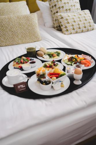 a tray with plates of food on a bed at Hotel Filmar in Toruń