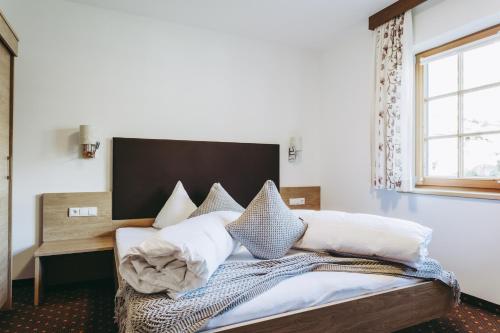 a bedroom with a bed with white pillows and a window at Andis Almdorf in Sölden