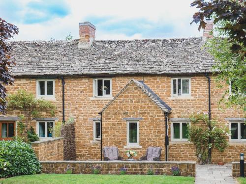 an old brick house with two chairs in front of it at Climbing Rose Cottage - Dog Friendly - Peaceful Cotswold Cottage in Adlestrop