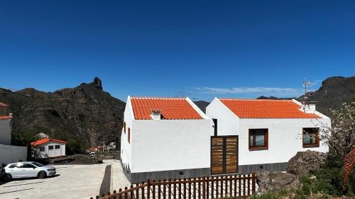 een wit huis met een oranje dak op een heuvel bij Calma Suites Tejeda in Tejeda