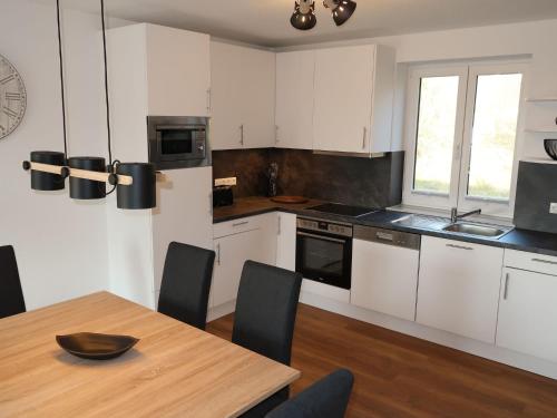 a kitchen with white cabinets and a wooden table at Holiday Home Cuxland Ferienpark-5 by Interhome in Wremen