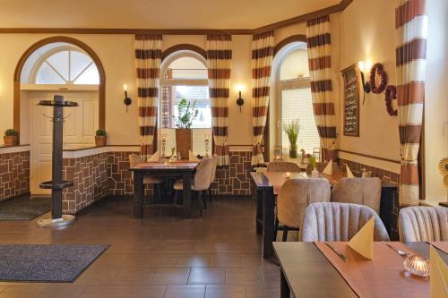 ein Restaurant mit Tischen und Stühlen und zwei Fenstern in der Unterkunft Hotel-Restaurant Holsteiner Hof in Geesthacht