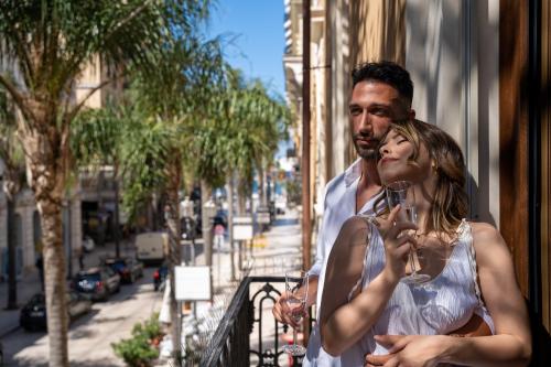 a man and a woman standing on a balcony holding wine glasses at Palazzo Bellocchi - Suites & Apartments in Brindisi