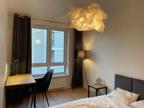 1 dormitorio con cama, escritorio y ventana en Blue Apartment, en Kielce
